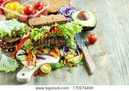 Vegan rye sandwich with fresh ingredients: avocado salad tomato carrots for healthy meal vitamin and diet food
