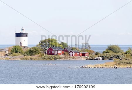 Lighthouse and some small red cottages on a tiny island in the swedish archipelago