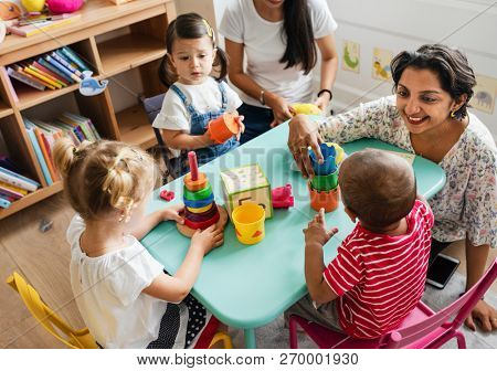 Nursery children playing with teacher in the classroom