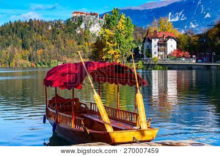 Pletna Tourist Boat, Castle And Autumn Colorful Trees Background In Slovenia, Lake Bled