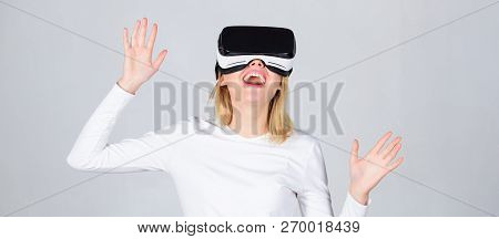 Portrait Of An Amazed Girl Using A Virtual Reality Headset Isolated On Grey Background. Happy Woman 