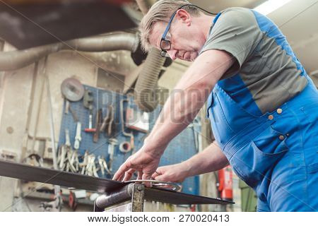 Metalworker man in his workshop working on project measuring and planning