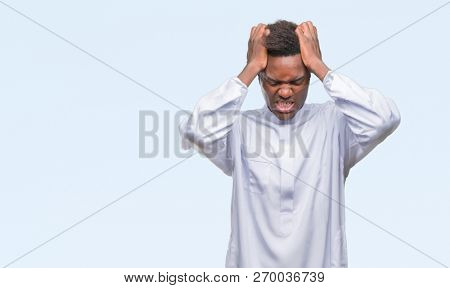 Young arabic african man wearing traditional djellaba over isolated background suffering from headache desperate and stressed because pain and migraine. Hands on head.