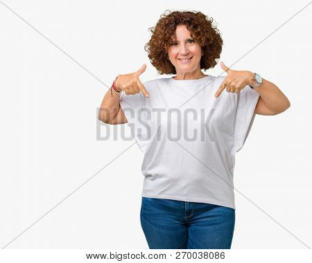 Beautiful middle ager senior woman wearing white t-shirt over isolated background looking confident with smile on face, pointing oneself with fingers proud and happy.