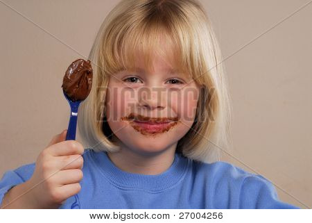 Lille pige spiser chokolade creme.Kid spise møtrik chokolade creme.