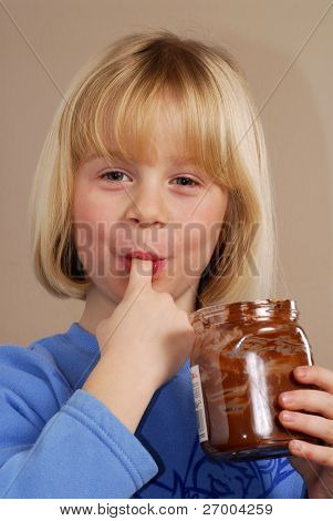 Lille pige spiser chokolade creme.Kid spise møtrik chokolade creme.
