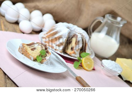 Cut Of Bundt Cake Sprinkled With Sugar, Lemon, Melissa, Milk, Eggs And Butter