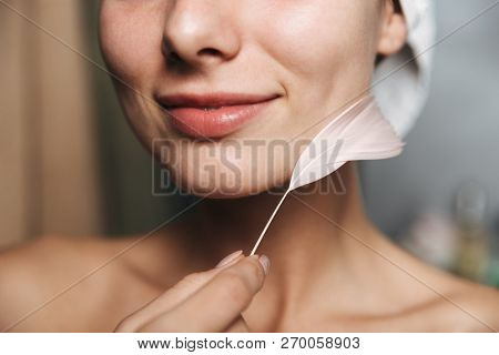 Close up pof pretty young woman wrapped in towel holding a feather indoors