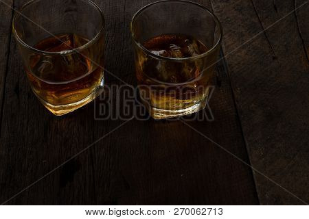 Glass Of Alcohol Scotch Whiskey With Ice On Wooden Table And Black Background