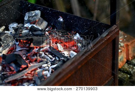 Burning Coals In The Barbecue On A Blurred Background, The Texture Of The Flame
