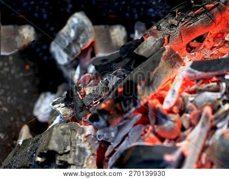 Burning Coals In The Barbecue On A Blurred Background, The Texture Of The Flame