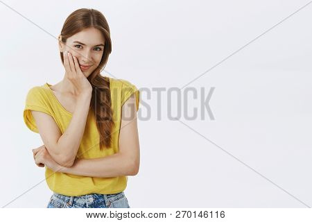 Waist-up Shot Of Cute Feminine Girlfriend In Yellow-thisrt Touching Cheek Gently Smiling Sensually A