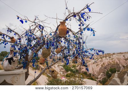 White Toy Swan Near The Tree Of Desires. Evil Eye In Tree Behind Uchisar Castle In Cappadocia, Uchis