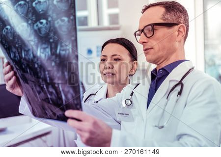Attentive Concentrated Medical Workers Examining X-ray Photo