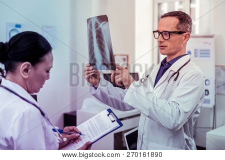 Competent Asian Doctor Filling Form During Research
