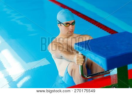 Photo of athlete swimmer in blue cap at side in pool