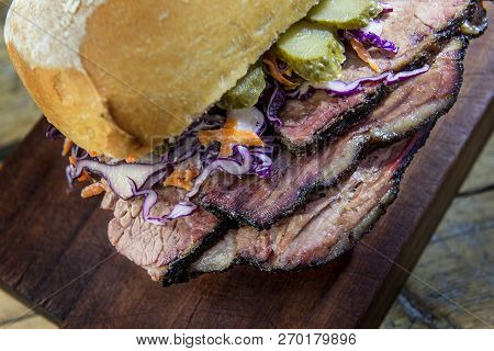 Detail Of Brisket Sandwich With Cucumber And Coleslow On Cutting Board