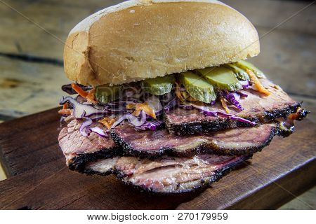 Detail Of Brisket Sandwich With Cucumber And Coleslow On Cutting Board