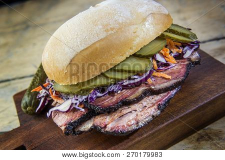 Detail Of Brisket Sandwich With Cucumber And Coleslow On Cutting Board