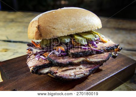 Detail Of Brisket Sandwich With Cucumber And Coleslow On Cutting Board