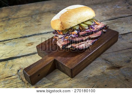 Brisket Sandwich With Cucumber And Coleslow On Cutting Board