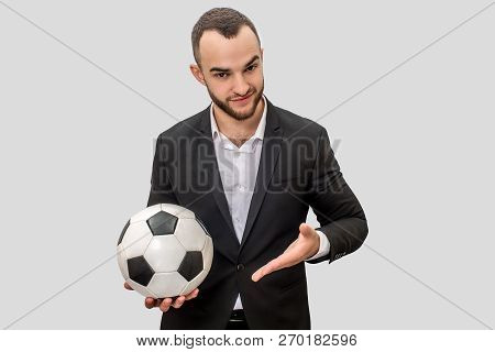 Confident Young Man In Suit Stands And Hold Ball For Playing Football. He Points On It With Hand. Is
