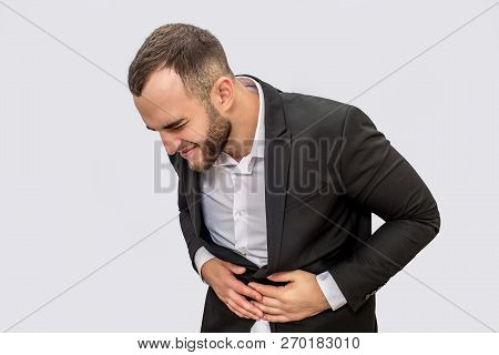 Businessman Suffers From Pain In Stomack Area. He Holds Both Hands There And Look Down. Isolated On 
