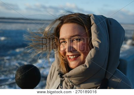 Portrait Of Pretty Cheerful Smiling Woman On Frozen River Background In Sunny Winter Day. Healthy Wi