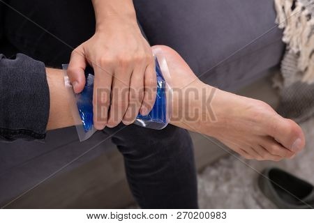 Close-up Of A Man Applying Ice Gel Pack On An Injured Ankle