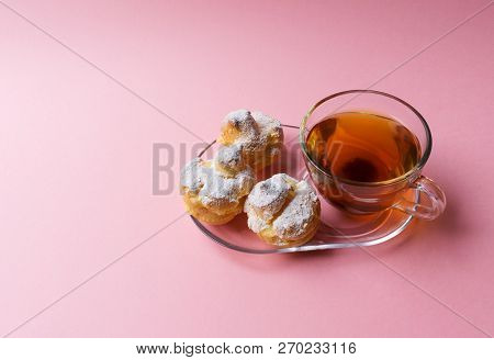 A Cup Of Green Tea And Three Profiteroles Sprinkled With Sugar Powder On A Pink Background. Stock Im