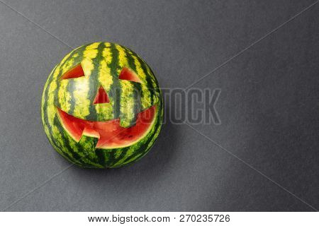 Halloween Watermelon With A Funny Face Closeup On A Dark Background. Copy Space For Text.