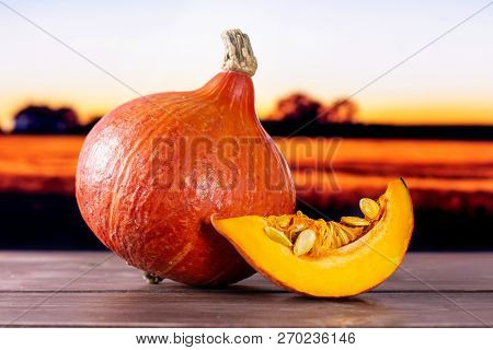 Group Of One Whole One Slice Of Fresh Red Kuri Pumpkin Hokkaido Variety With Autumn Field And Sunset