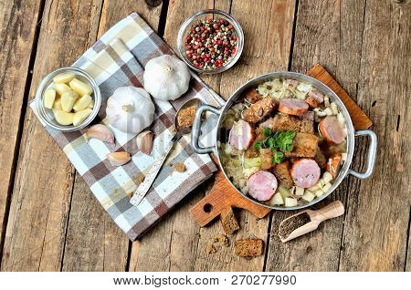 View From Above Of Garlic Soup In An Old Saucepan, Sausage, Fresh Garlic Bulbs, Cloves, Colored Pepp