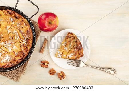A Photo Of An Apple Pie In A Pan And A Slice Of It On A Plate, Shot From The Top On A Rustic Wooden 
