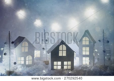 Christmas And New Year Miniature Magical House In The Snow At Night And Bokeh City Lights. Christmas