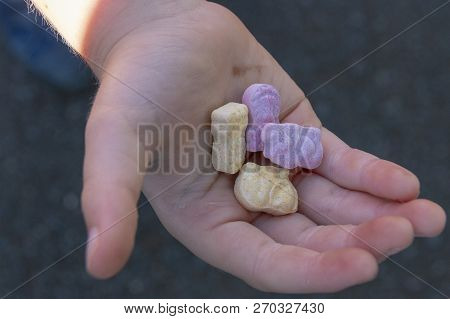 A Close Up View Of A Small Child Holding Four Animal Shaped Vitamins In The Plam Of His Hand