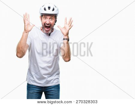 Middle age senior hoary cyclist man wearing bike safety helment isolated background celebrating crazy and amazed for success with arms raised and open eyes screaming excited. Winner concept