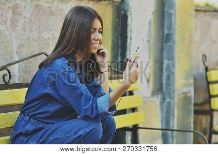 Young Beautiful Asian Girl Sitting On A Bench Talking On The Phone, Horizontal Photo, Campus