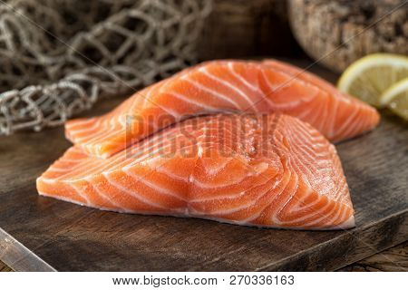Fresh Raw Salmon Fillets On A Wooden Board With Lemon And Fish Net Background.