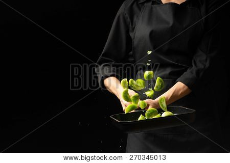 The Chef Cooks Green Tomatoes On The Pan. Black Background For Copying Text. Restaurant Business And
