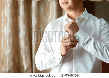 The Man In The White Shirt Adjusts His Cufflinks On The Sleeves. Elegant Fashion Businessman Fixing 