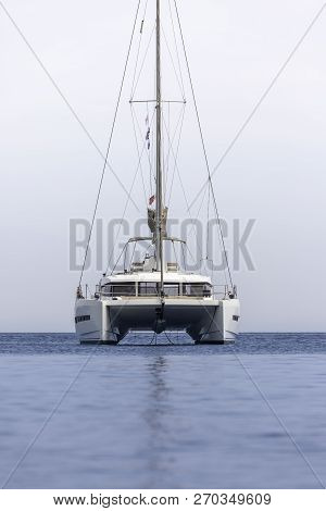 White Sailing Boat Catamaran On Ocean Near Beach.