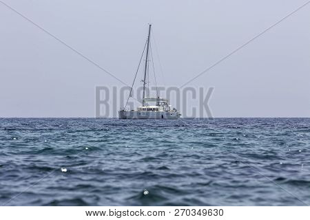 White Sailing Boat Catamaran On Ocean Near Beach.