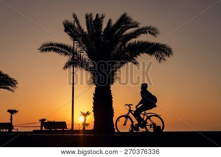 Batumi, Georgia, April 7, 2018: Silhouette Of A Boy Riding On A Bike, Sunset Sky Background