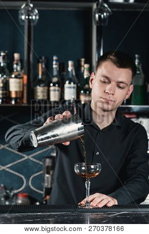 Bartender Making Boulevardier Cocktail Pouring Fluid Into Glass. Bar On A Background