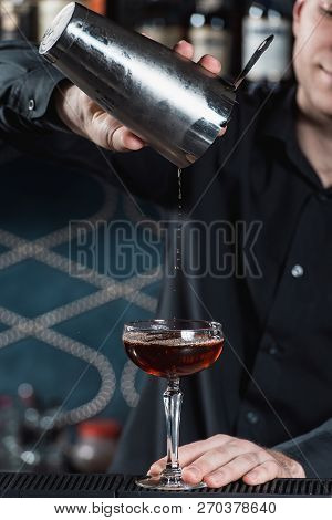 Bartender Making Boulevardier Cocktail Pouring Fluid Into Glass. Bar On A Background