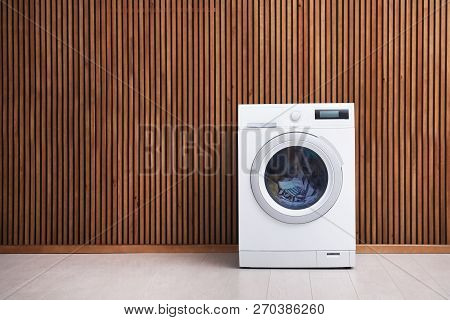 Washing Machine With Laundry Near Wooden Wall. Space For Text