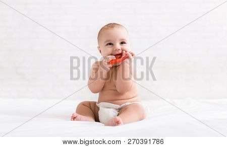 Infant Growing First Tooth. Cute Newborn Baby Biting Teether In Bed, Copy Space