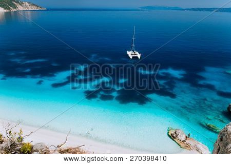 White Catamaran Yacht Drift On Clear Azure Water Surface In Calm Blue Lagoon With Transparent Water 