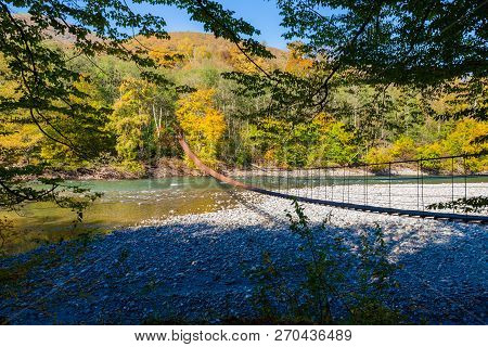 Narrow Metal Foot Bridge Across Mountain River In Autumn.